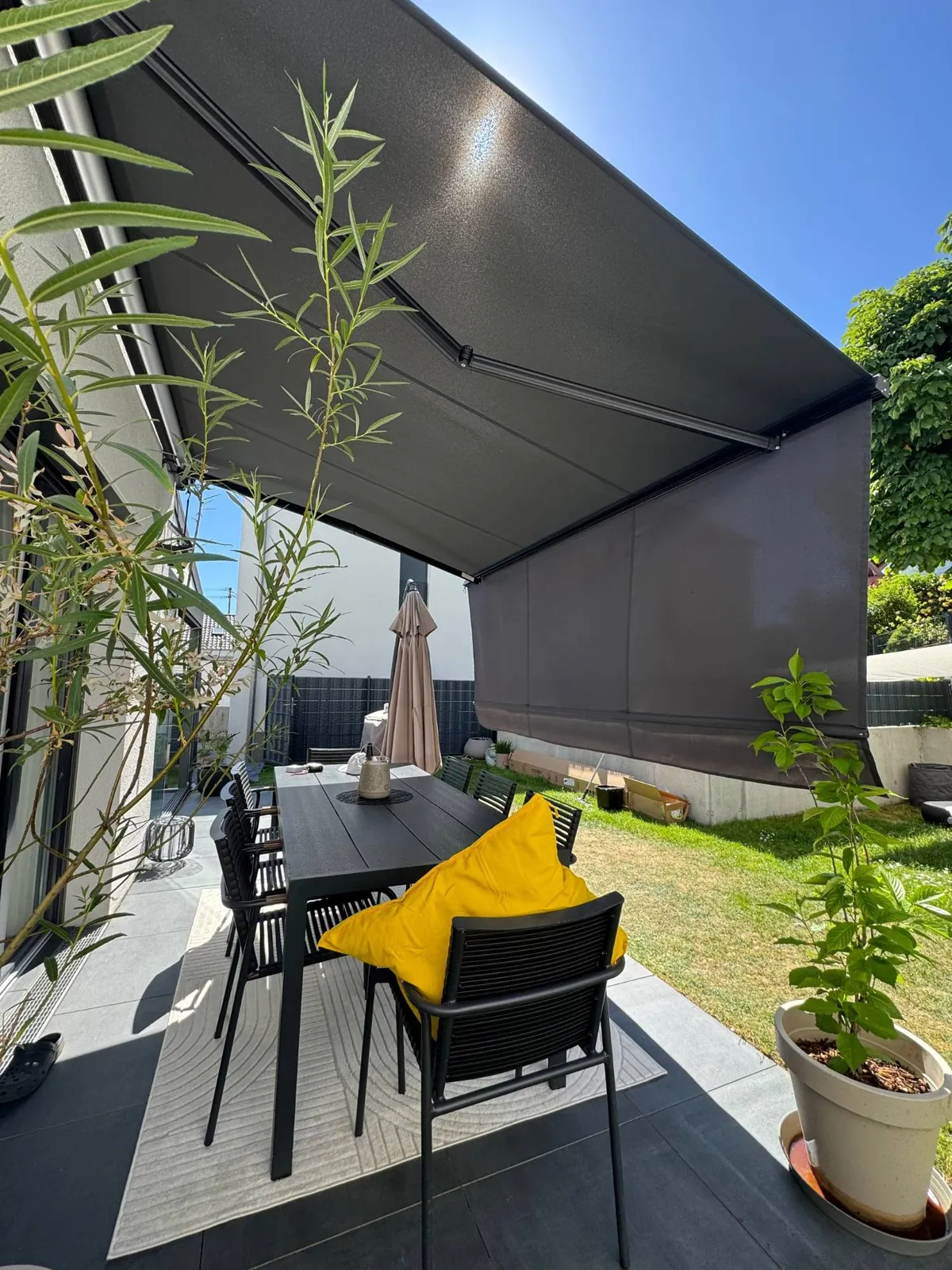 Markise mit Senkrechtmarkise über einer Terrasse mit Sitzgruppe