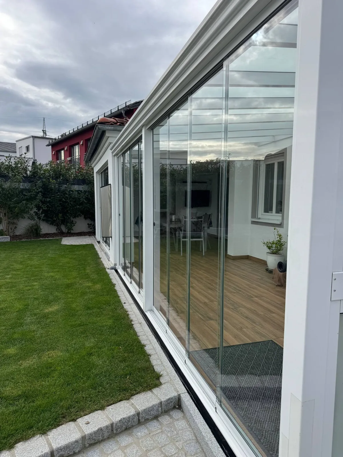 Wintergarten in Weiß mit Glasschiebewänden und Blick in den Garten