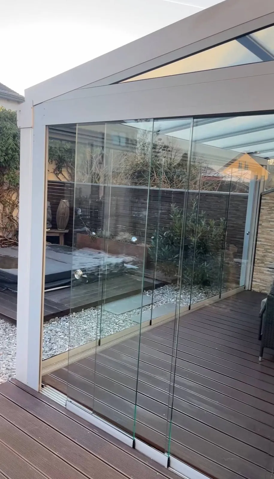 Wintergarten in hellem Grau mit Holzdielen und Glasschiebewänden