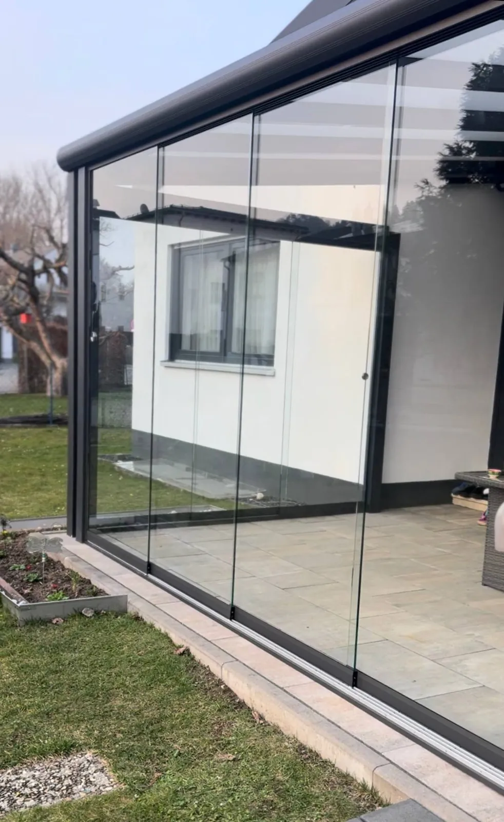 Verglaster Wintergarten mit Glasschiebewänden und Blick in den Garten