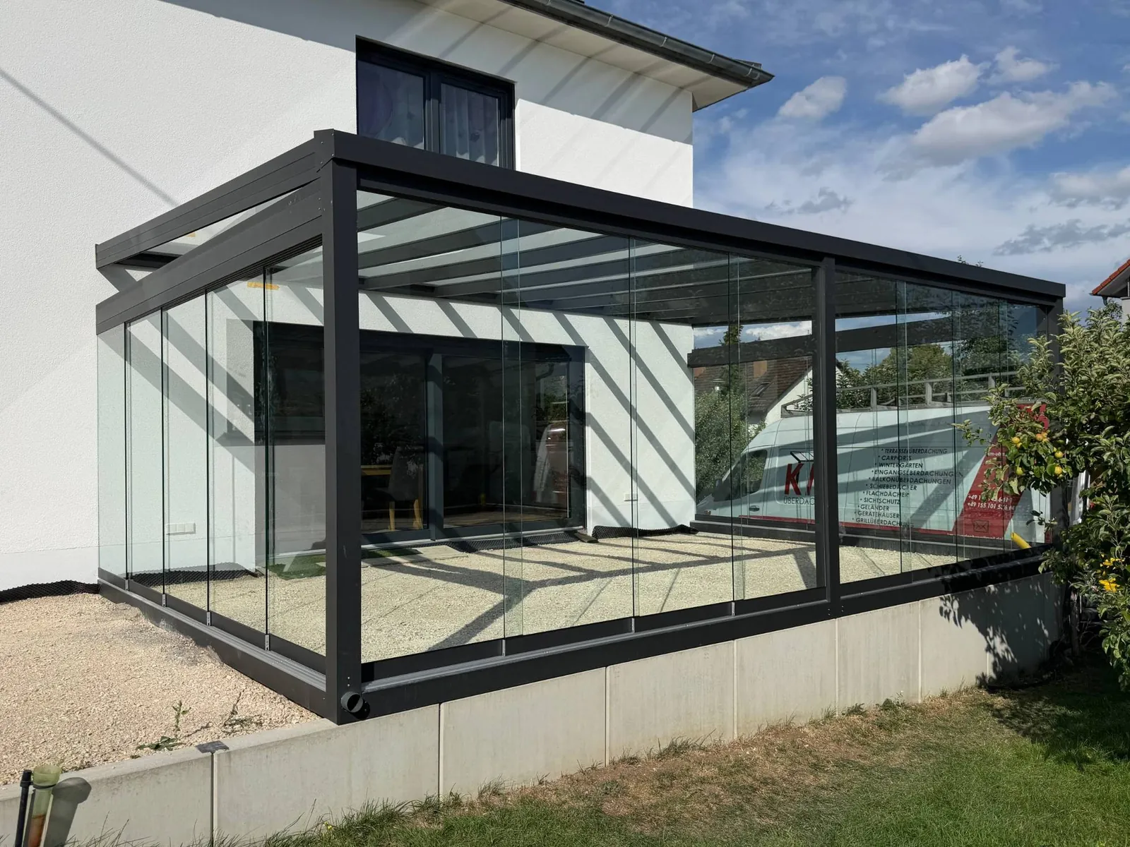 Anthrazitfarbener Wintergarten mit Glasschiebewänden an einem Wohnhaus