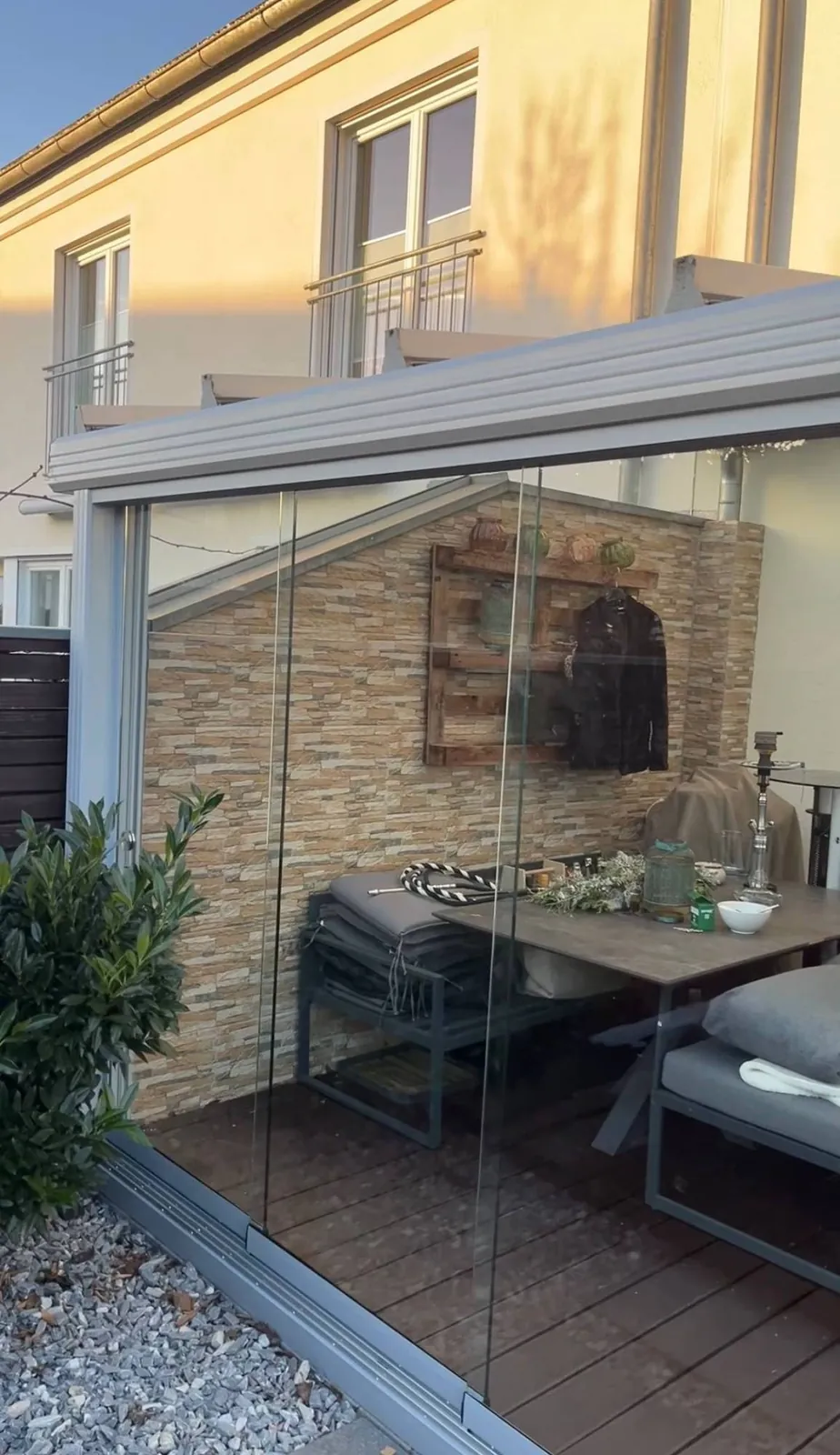 Verglaste Terrasse mit Steinwand und Sitzbereich