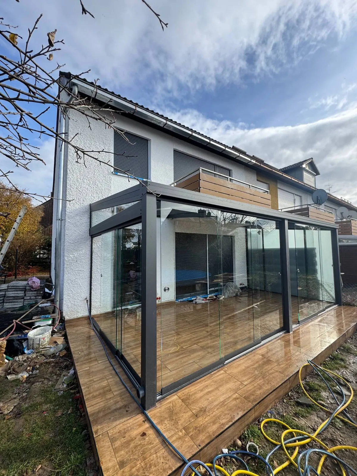 Frisch montierter Wintergarten mit Glasschiebewänden und Holzoptik-Boden